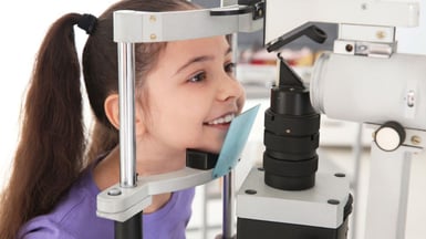 Optometrist examining a young child’s eyes during an eye exam